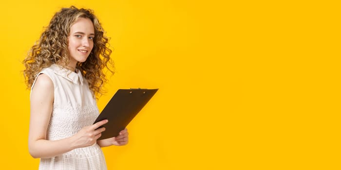 Portrait of a young woman who holds a tablet in her hands. Female portrait. Isolated on yellow background