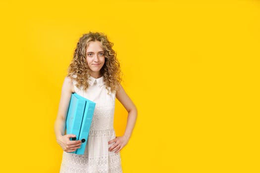 A young woman holds folders with documents in her hands. Isolated on yellow background