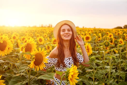 Portrait of young cute woman in straw hat . Outdoors on the sunflower field. Caucasian girl in casual clothes at sunset enjoying the evening in a field of bright sunflowers