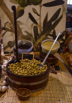 a large wooden container with olives with garlic and sauces in a shop in France