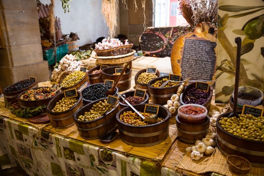 Uatun,france,24-08-2022: large wooden containers with olives with garlic and sauces in a shop in France