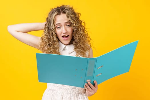 A young woman holds folders with documents in her hands. Reads and wonders. Isolated on yellow background