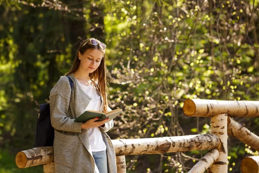 Young caucasian woman in the park reading a book on a spring sunny day,