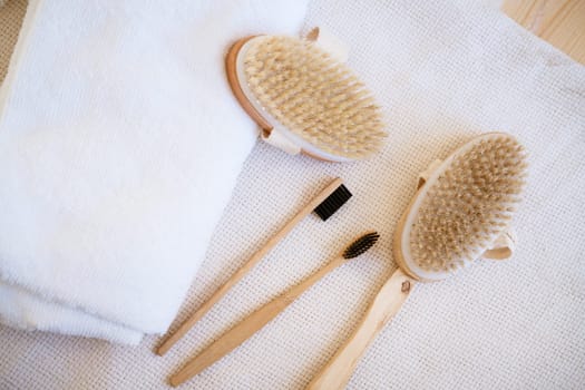 natural wooden massage brushes and dental brushes on a background with a white clothier, the concept of environmentally friendly items for body care