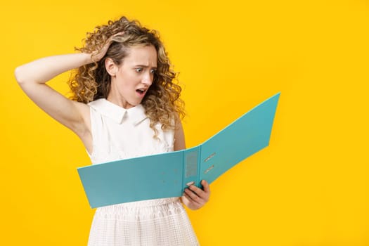 A young woman holds folders with documents in her hands. Reads and wonders. Isolated on yellow background