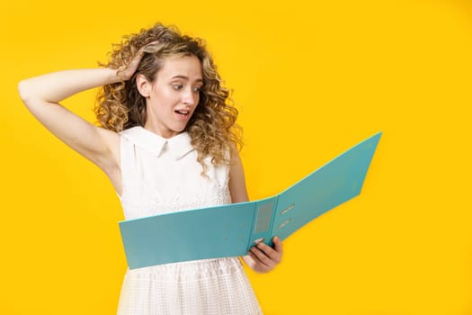 A young woman holds folders with documents in her hands. Reads and wonders. Isolated on yellow background