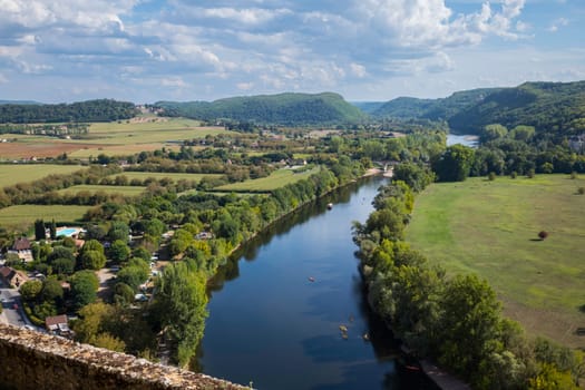 the Dordogne river with links a campsite seen from the castle of beynac with the hills and boats on the river in the background