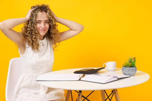 A young woman sits at a table, works with documents, considers, studies. Education. Business. Isolated on yellow background