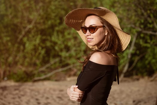 Close-up portrait of a woman in a hat from the sun on a summer sunny day. Beautiful caucasian young woman posing in sunglasses outdoors in the afternoon cute smiling