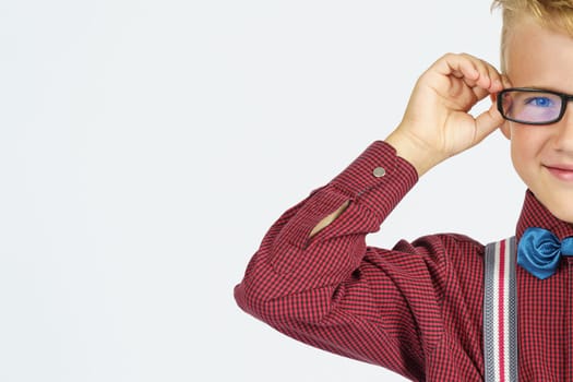 A portrait of a schoolboy adjusting his glasses. Education concept.