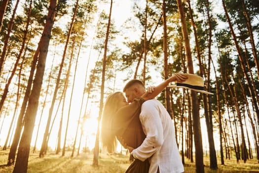 Against background with sunshine. Happy couple is outdoors in the forest at daytime.