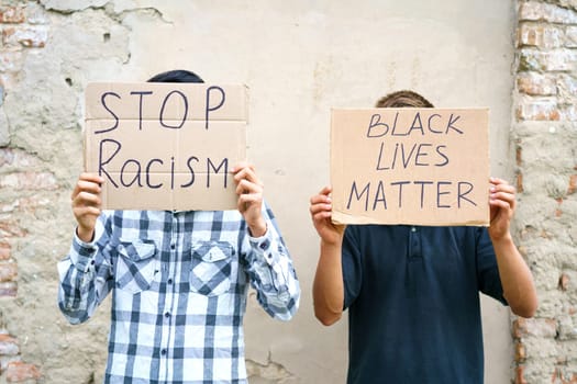 Poster that says black life matters and stop racism in the hands of a young man. Caucasian guy staged a protest demonstration against racism, wrote a slogan on cardboard