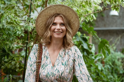 cute young blonde woman posing and smiling among the greenery in the greenhouse