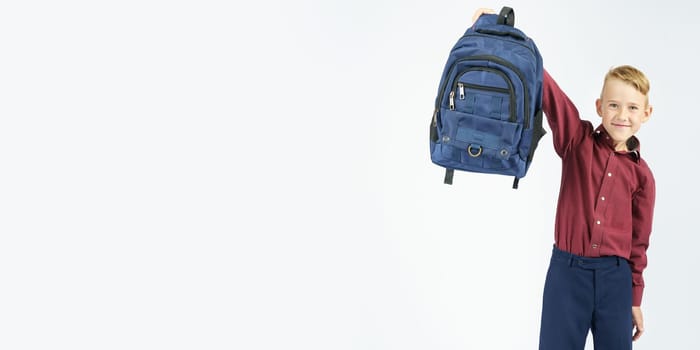 A schoolboy holds a schoolbag lifting it up. Education concept