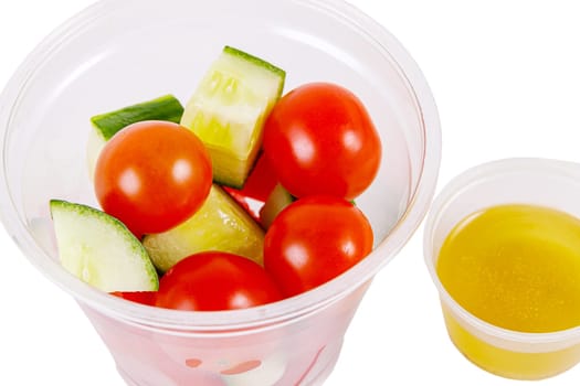 Salad of cucumbers, cherry tomatoes, peppers and dressing on a white background. Side view. Isolate