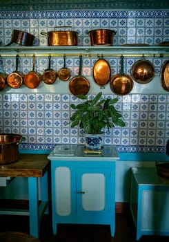 old kitchen with copper pans on the wall and blue tiles on the wall above a number of blue cupboards