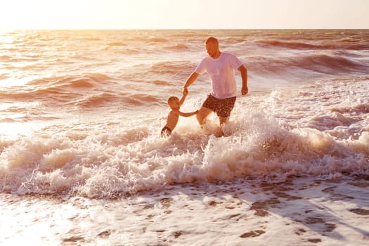 Happy dad and son swim in the sea. Holidays for the whole family. The child splashes in the waves. Splashing water and sea foam