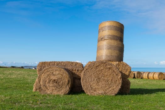 hay bales in the shape of an agricultural tractor on the hilly landscape of the opal coast near cap blanc nez in france with the canal between france and england in the background on a summer day