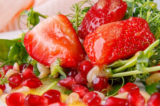 Salad with microgreens, strawberries, pine nuts and pomegranate seeds. Close-up