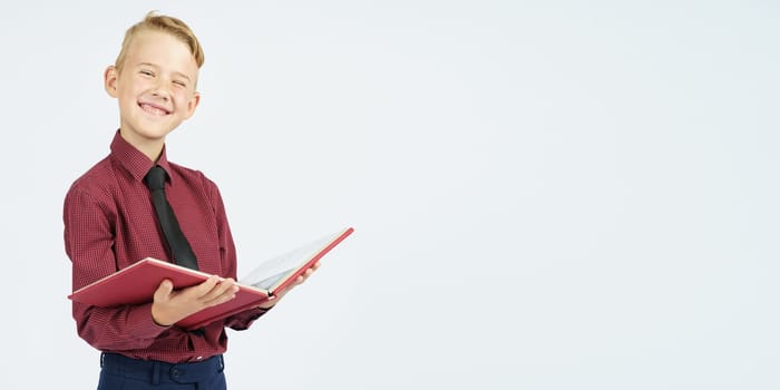 Pupil holding an open book and smiling, isolated background. Education concept