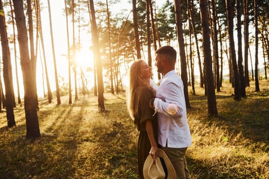Embracing and kissing. Happy couple is outdoors in the forest at daytime.