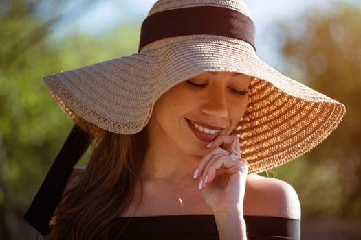 Cheerful young woman in straw sun hat smiles toothy smile close up on summer sunny day