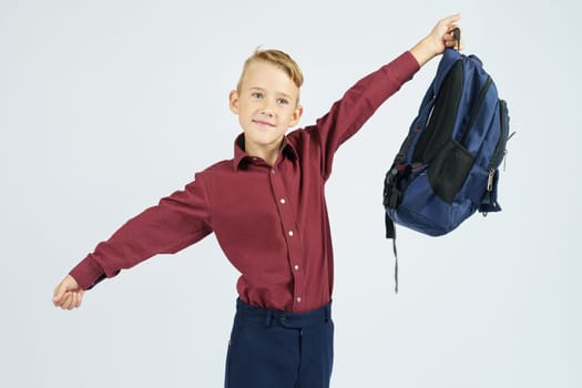 A schoolboy holds a schoolbag lifting it up. Education concept
