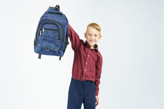 A schoolboy holds a schoolbag lifting it up. Education concept