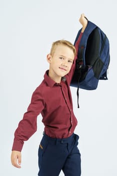 A schoolboy holds a schoolbag lifting it up. Education concept