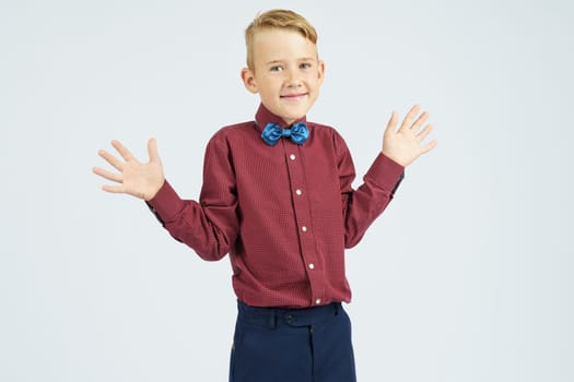 A portrait of a schoolboy who raised his hands in surprise and joy. Isolated background. Education concept.