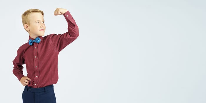 A portrait of a schoolboy who demonstrates his strength. Isolated background. Education concept.