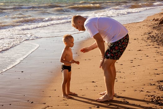 Dad with his son on the beach. Young caucasian father with happy child on vacation on a sunny day