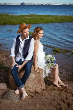 happy caucasian couple man and woman on the beach, summer day holding a bouquet of flowers in her hand