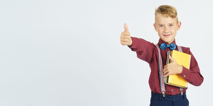 The student holds books in his hands and shows a gesture okay, smiles. Isolated background. Education concept