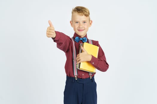 The student holds books in his hands and shows a gesture okay, smiles. Isolated background. Education concept