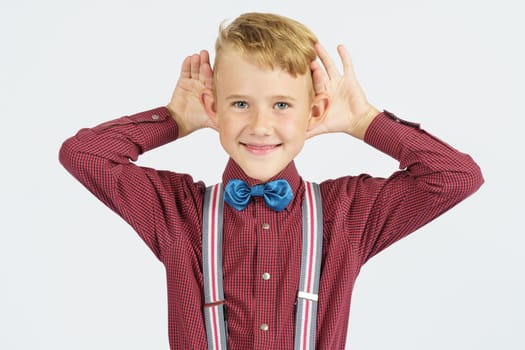 A portrait of a schoolboy who pretends to hear poorly. Isolated background. Education concept.