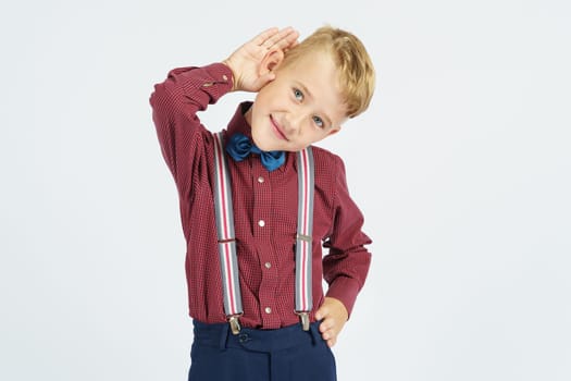 A portrait of a schoolboy who pretends to hear poorly. Isolated background. Education concept.