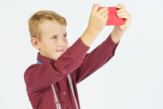 Portrait of a schoolboy taking a selfie on a mobile phone. Isolated background. Education concept.