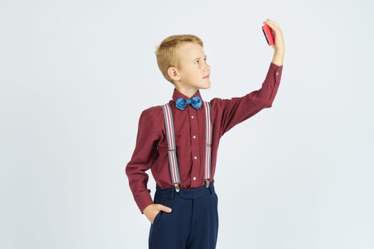 Portrait of a schoolboy taking a selfie on a mobile phone. Isolated background. Education concept.