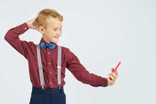 Portrait of a schoolboy taking a selfie on a mobile phone. Isolated background. Education concept.