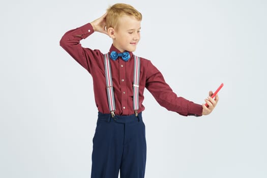 Portrait of a schoolboy taking a selfie on a mobile phone. Isolated background. Education concept.