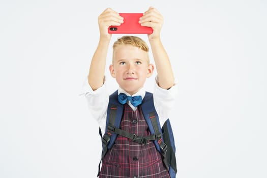 Portrait of a schoolboy taking a selfie on a mobile phone. Isolated background. Education concept.
