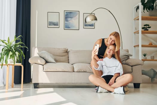 Making selfie. Female teenager with her mother is at home at daytime.