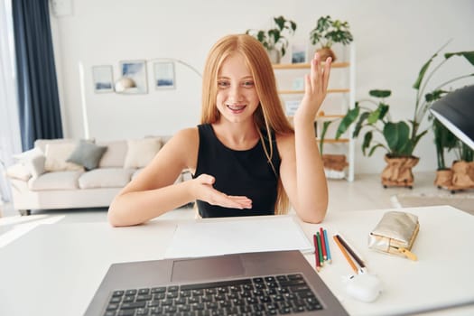 Online education. Female teenager with blonde hair is at home at daytime.
