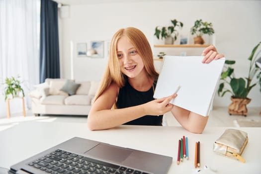 Online school. Female teenager with blonde hair is at home at daytime.