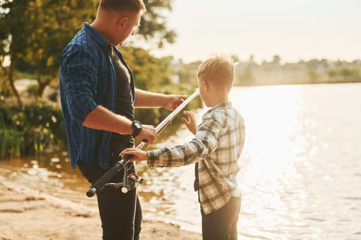 Father and son on fishing together outdoors at summertime.
