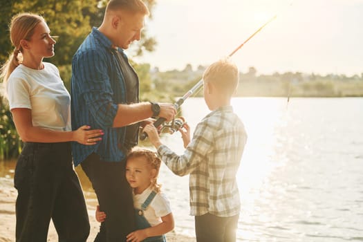 Conception of vacation. Father and mother with son and daughter on fishing together outdoors at summertime.