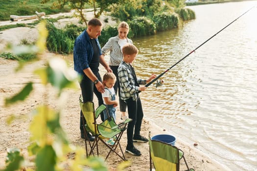 Conception of vacation. Father and mother with son and daughter on fishing together outdoors at summertime.