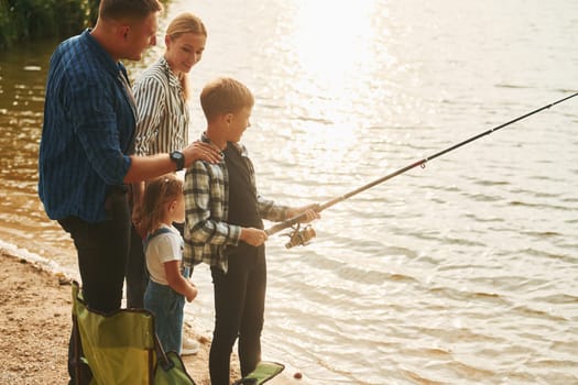 Conception of vacation. Father and mother with son and daughter on fishing together outdoors at summertime.