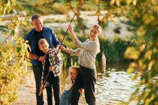 Father and mother with son and daughter on fishing together outdoors at summertime.